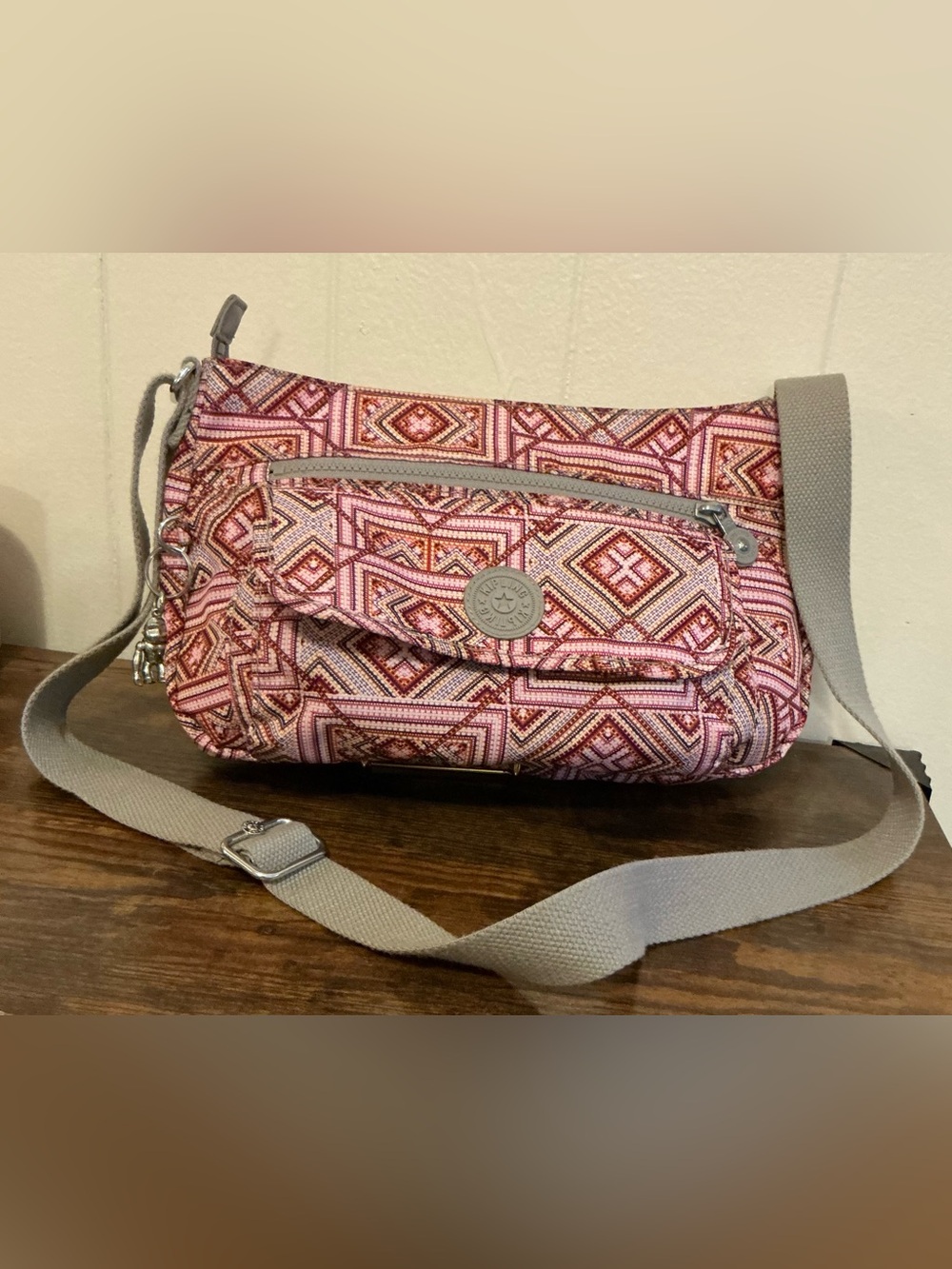 A Kipling Syro crossbody shoulder bag in a pink and grey geometric print Handbag